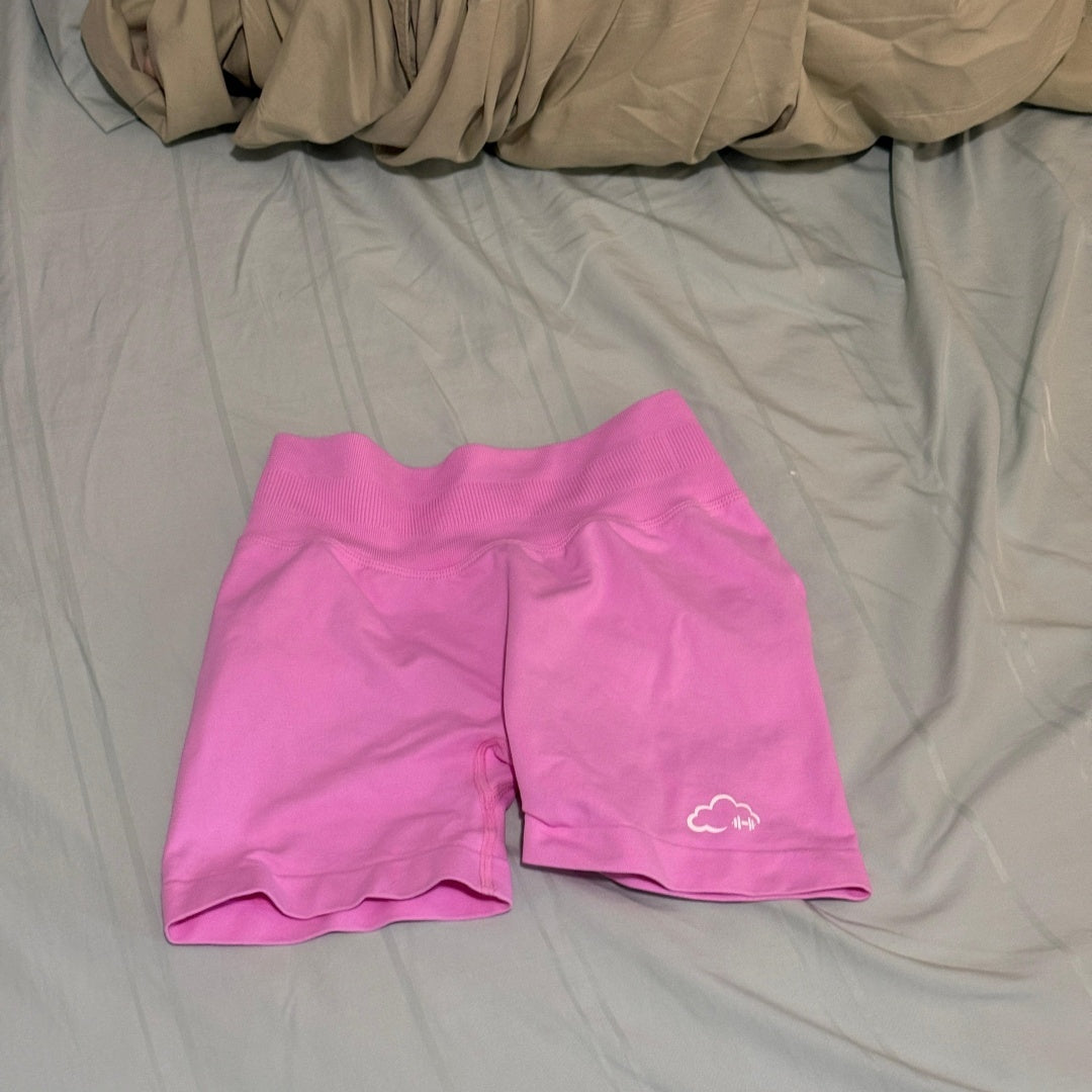 Pink shorts with a cloud logo on a gray bedspread